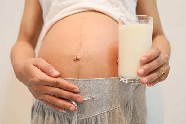 임산부 뱃속에 손에 음료 우유 잔을 보유. — 스톡 사진