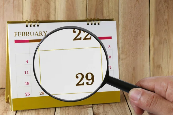 Magnifying glass in hand on calendar you can look Twenty-nine da — Stock Photo, Image
