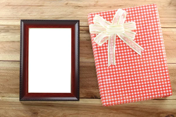 Rode geschenkdoos met lege houten fotolijst op houten achtergrond. — Stockfoto