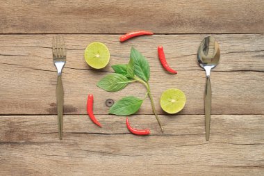 Gümüş kaşık ve çatal biber ve limon ile kahverengi ahşap üzerine baharatlı yiyecekler kavramı içinde yer.