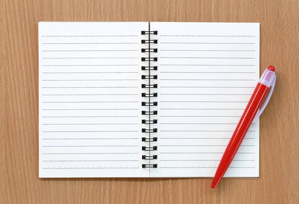 空のノートと赤ペンは茶色の木製の背景上に配置 — ストック写真