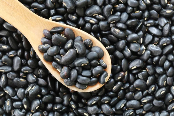 Black bean pile and wooden spoon of Tropical vegetables. — Stock Photo, Image