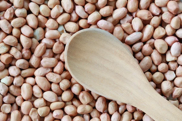 Empty wooden spoon on pile peanut background. — Stock Photo, Image