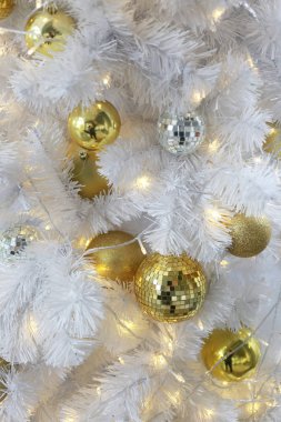 Beyaz bir Noel ağacına asılı altın top.