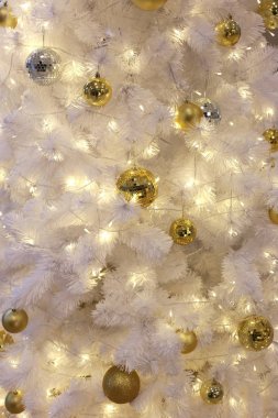 Beyaz bir Noel ağacına asılı altın top.