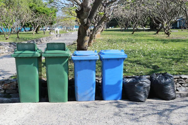Plastikmülleimer und schwarze Mülltüte im Park platziert. — Stockfoto