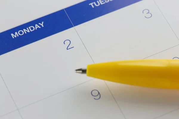 Желтая ручка указывает на число 2 на фоне календаря . — стоковое фото