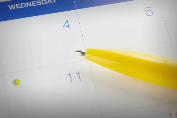 Pluma amarilla apunta al número 4 en el fondo del calendario . — Foto de Stock