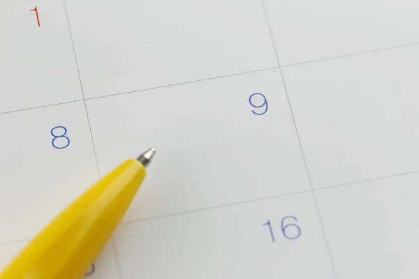 Pluma amarilla apunta al número 9 en el fondo del calendario . — Foto de Stock