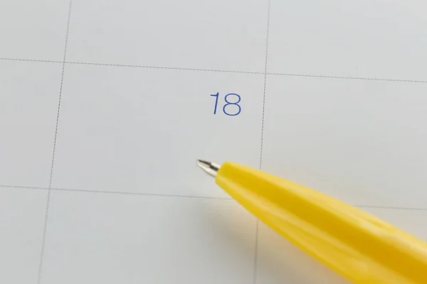 Gul penna punkter till nummer 18 på kalender bakgrund. — Stockfoto