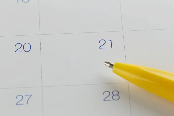 Pluma amarilla apunta al número 21 en el fondo del calendario . — Foto de Stock