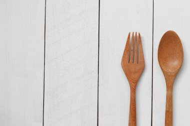 Tahta kaşık ve Beyaz ahşap zemin üzerinde ahşap çatal.