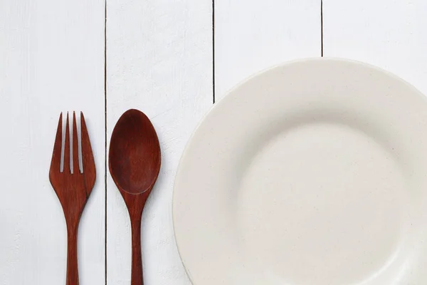 Assiette et cuillère sur plancher de bois blanc . — Photo