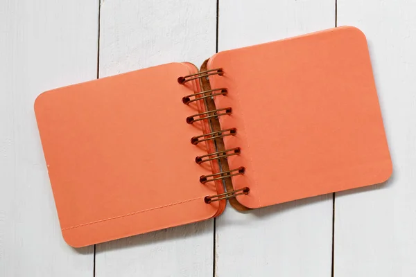 Quaderno arancione posto su un pavimento di legno bianco . — Foto Stock