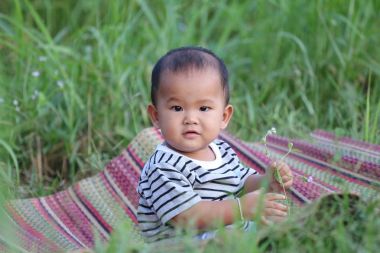 Asyalı çocuk çocuk Tay mat bahçede oturmak.