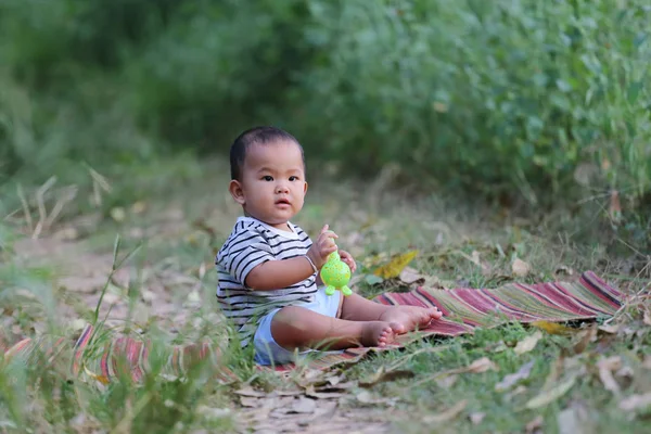 Asyalı çocuk çocuk Tay mat bahçede oturmak.