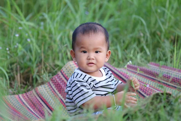 Asyalı çocuk çocuk Tay mat bahçede oturmak.