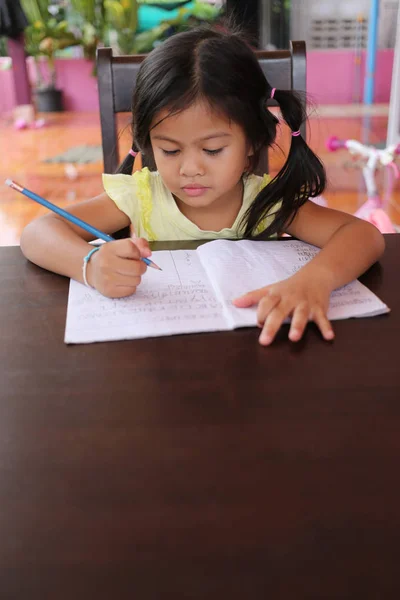Asiática niña uso Lápiz escribir cartas en el libro . — Foto de Stock