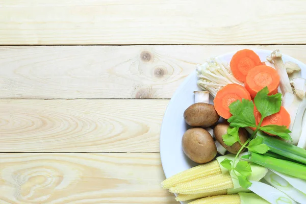 Verse groenten in een witte schotel worden geplaatst op een bruin hout brandstof — Stockfoto