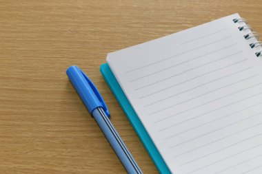 Kahverengi bir ahşap zemin üzerinde yerleştirilen boş defter ve renk kalem.