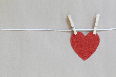 Kırmızı kalp bir ip üzerinde asılı ve kahverengi backgro kopya alanınız