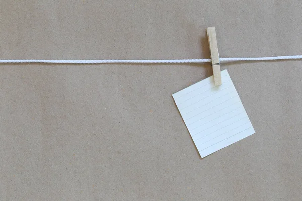 Kladblok lege opknoping op een touw en bruine papieren achtergrond. — Stockfoto