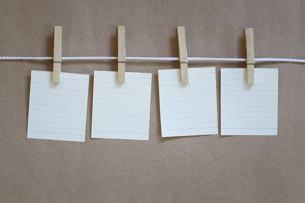 Bloc de notas vacío colgado en una cuerda y fondo de papel marrón . — Foto de Stock