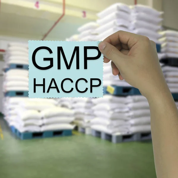 Main de l'homme d'affaires tenant une note papier avec GMP et HACCP — Photo