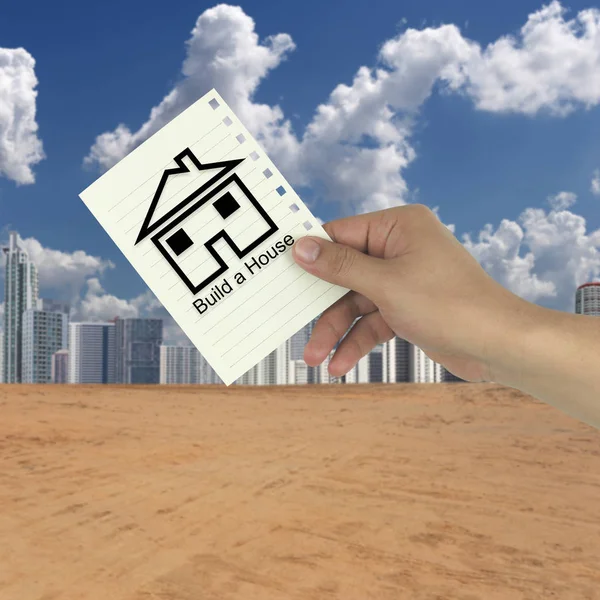 Hand of the businessman holding a paper note with build a house — Stock Photo, Image