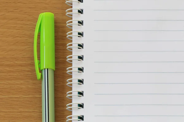 Notebook e penne sono posizionati su un pavimento di legno marrone . — Foto Stock