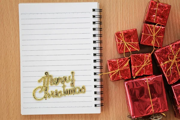 Leeres Notizbuch in der Nähe der roten Geschenkbox auf einem braunen Holzfl — Stockfoto