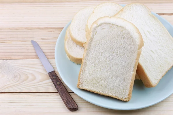 Ψωμί σε φέτες σωρευμένες σε πράσινο πιάτο σε ξύλινο δάπεδο. — Φωτογραφία Αρχείου