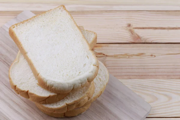 Brot in Scheiben gestapelt auf einem hölzernen Schneidebrett. — Stockfoto