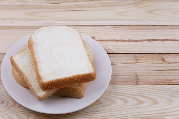 Ψωμί σε φέτες σωρευμένες σε πιάτο σε ξύλινο δάπεδο. — Φωτογραφία Αρχείου