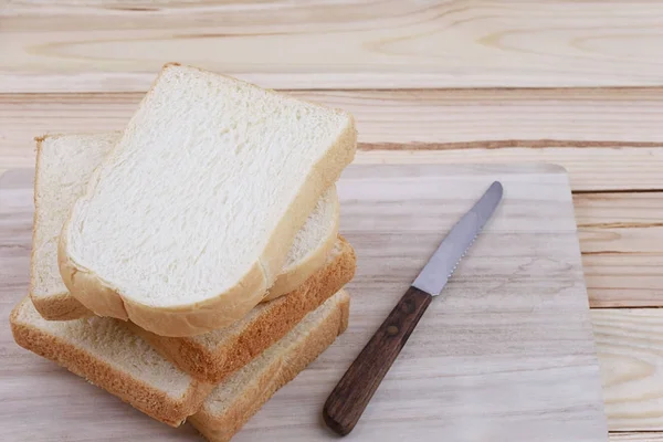 Brot in Scheiben gestapelt auf einem hölzernen Schneidebrett. — Stockfoto