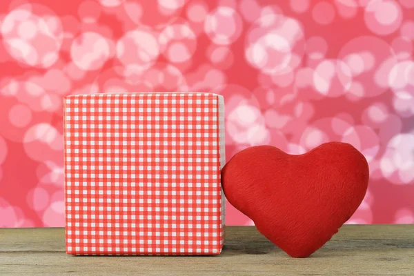 Cuore rosso e confezione regalo posta su un pavimento di legno su un bokeh rosso b — Foto Stock