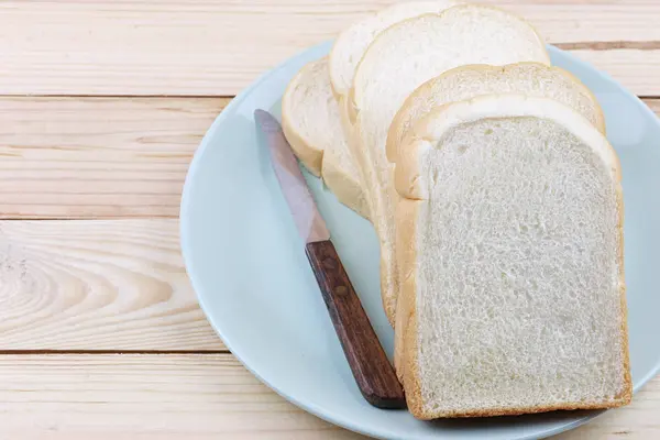 Scheibenbrot in grüner Schüssel auf Holzboden gestapelt. — Stockfoto