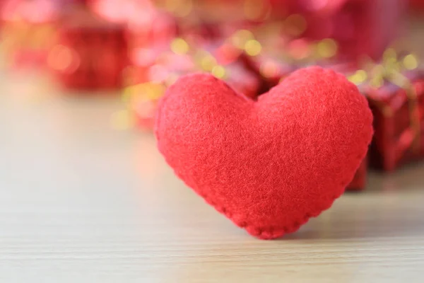 Coeur rouge placé sur un plancher de bois sur boîte cadeau rouge de backg flou — Photo