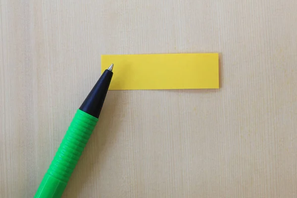 Lápiz verde que apunta a la nota de papel amarillo vacío en ba piso de madera — Foto de Stock