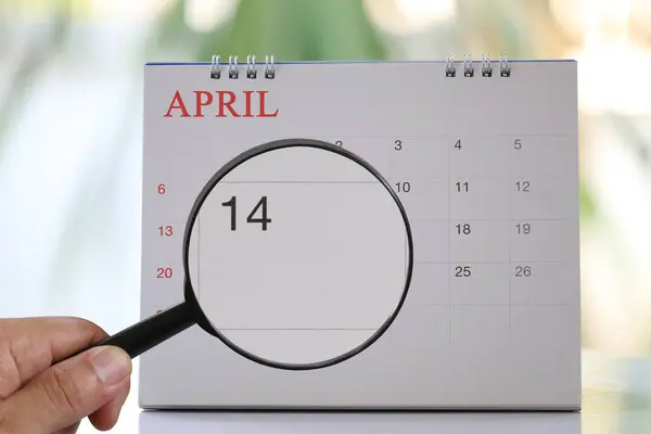 Förstoringsglas i hand på kalender kan du se fjortonde dagen — Stockfoto