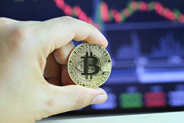İşadamı dijital grafik arka planı üzerinde elinde altın bitcoin.