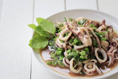 Fesleğenli ahşap zemin üzerinde beyaz tabak kalamar puf.