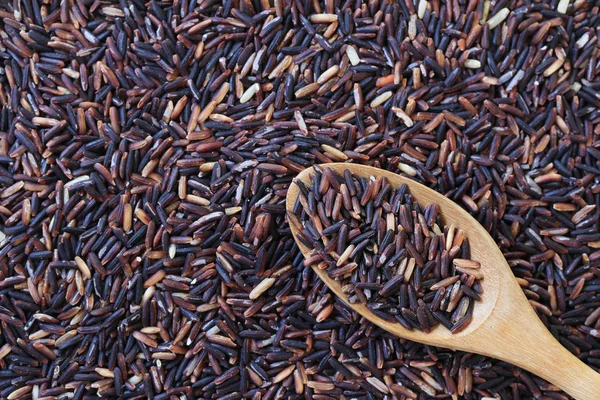 Жасмин рис в деревянной ложке на коричневом рисовом фоне . — стоковое фото