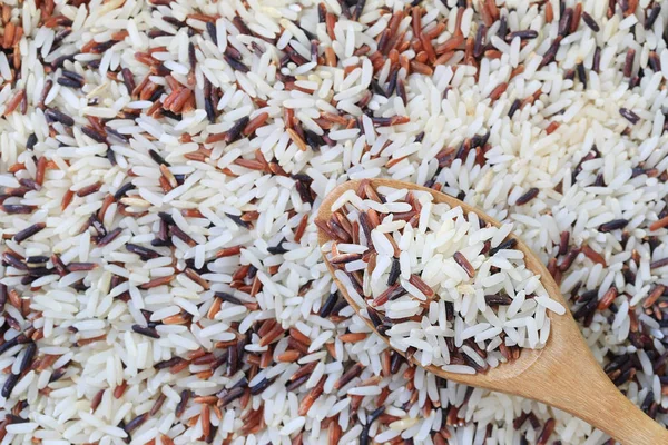 Jasmijn rijst in houten lepel op bruine rijst achtergrond. — Stockfoto