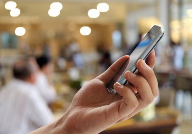 Adamın elini tutan bir smartphone bulanıklık Restoran arka plan üzerinde ve