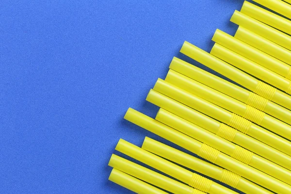 Yellow drinking straw in a blue paper background. — ストック写真