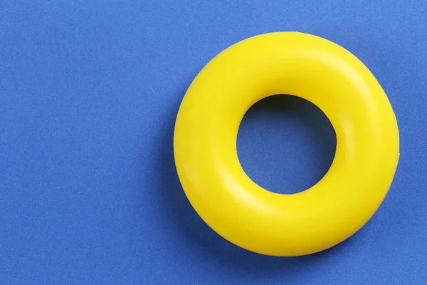 Gele rubberen ring geplaatst op een blauwe papieren ondergrond. — Stockfoto