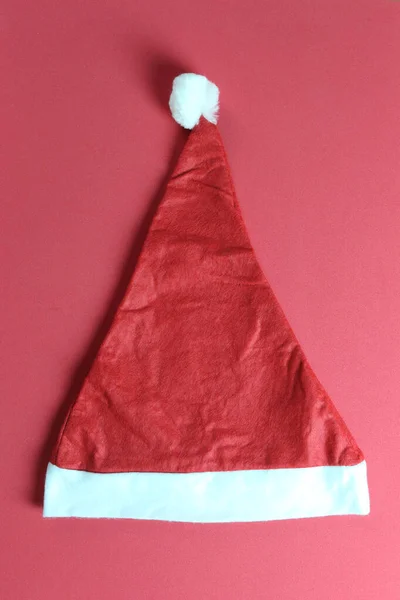 Santa hatt på röd konst papper bakgrund. — Stockfoto