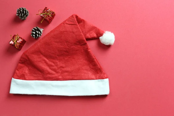 Santa kapelusz na czerwonym tle papieru artystycznego. — Zdjęcie stockowe