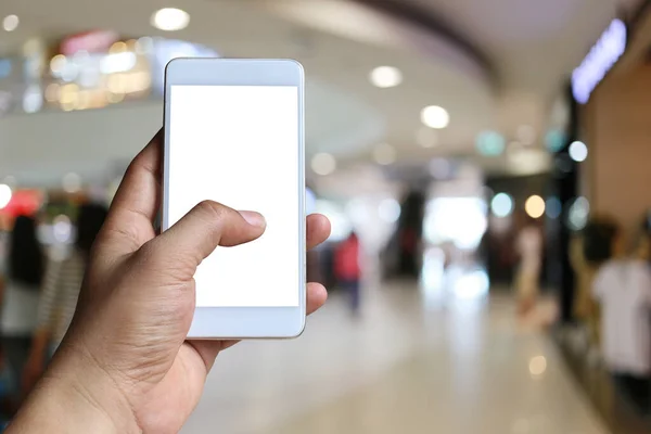 Mão de um homem segurando dispositivo smartphone no borrão Shopping mal — Fotografia de Stock